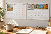 Calendario 2027 impreso en la pared de un despacho: la hoja de mayo con una acuarela de amapolas y la vista anual con un paisaje de las cuatro estaciones