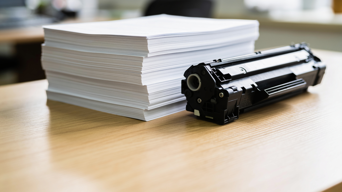 Pila de folios impresos junto a un cartucho de tóner