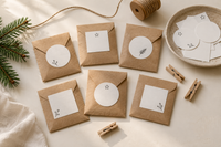 Buste di carta kraft con etichette bianche, spago e mollette su un tavolo da lavoro creativo